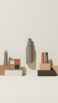 Greige liquid foundation bottle, Three-quarter product angles on compact blocks matching the brand’s neutral palette;...