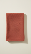 A perfectly centered image of a cotton kitchen towel in Tomato Red, displayed against a plain, light-colored background....